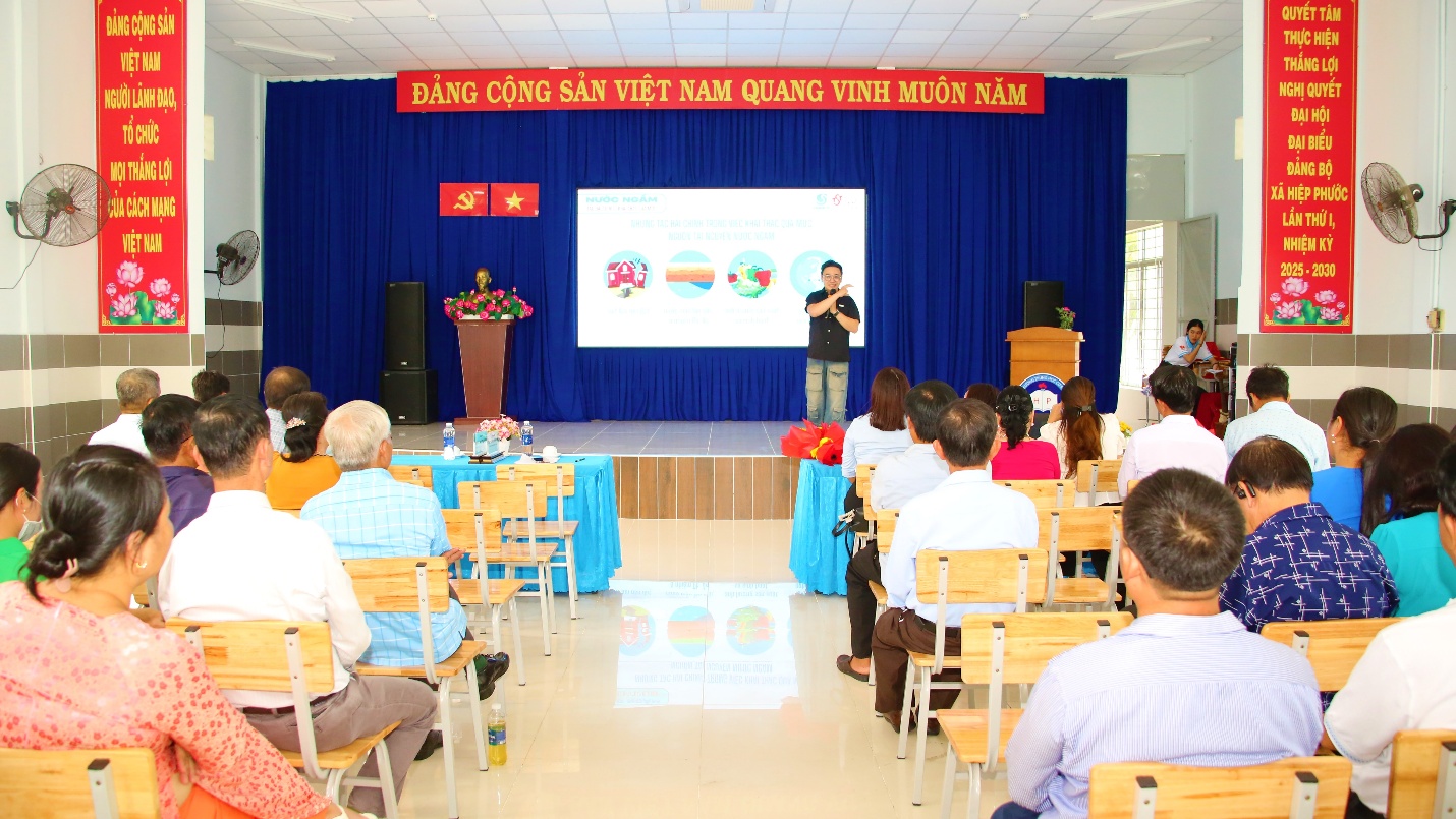 A person standing in front of a stage with a presentation

Description automatically generated